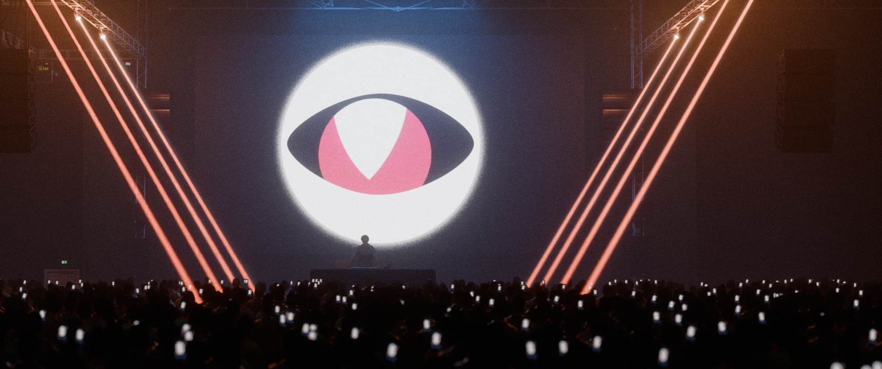 Große DJ-Bühne mit vielen Zuschauern und Lasern. Hinter dem DJ befindet sich das Logo von ManicVisin: Ein schwarzes Auge mit roter Pupille, welche ein M und V symbolisiert